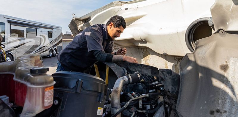 Truck cab being worked on in a garage. Hood up, tools scattered around.