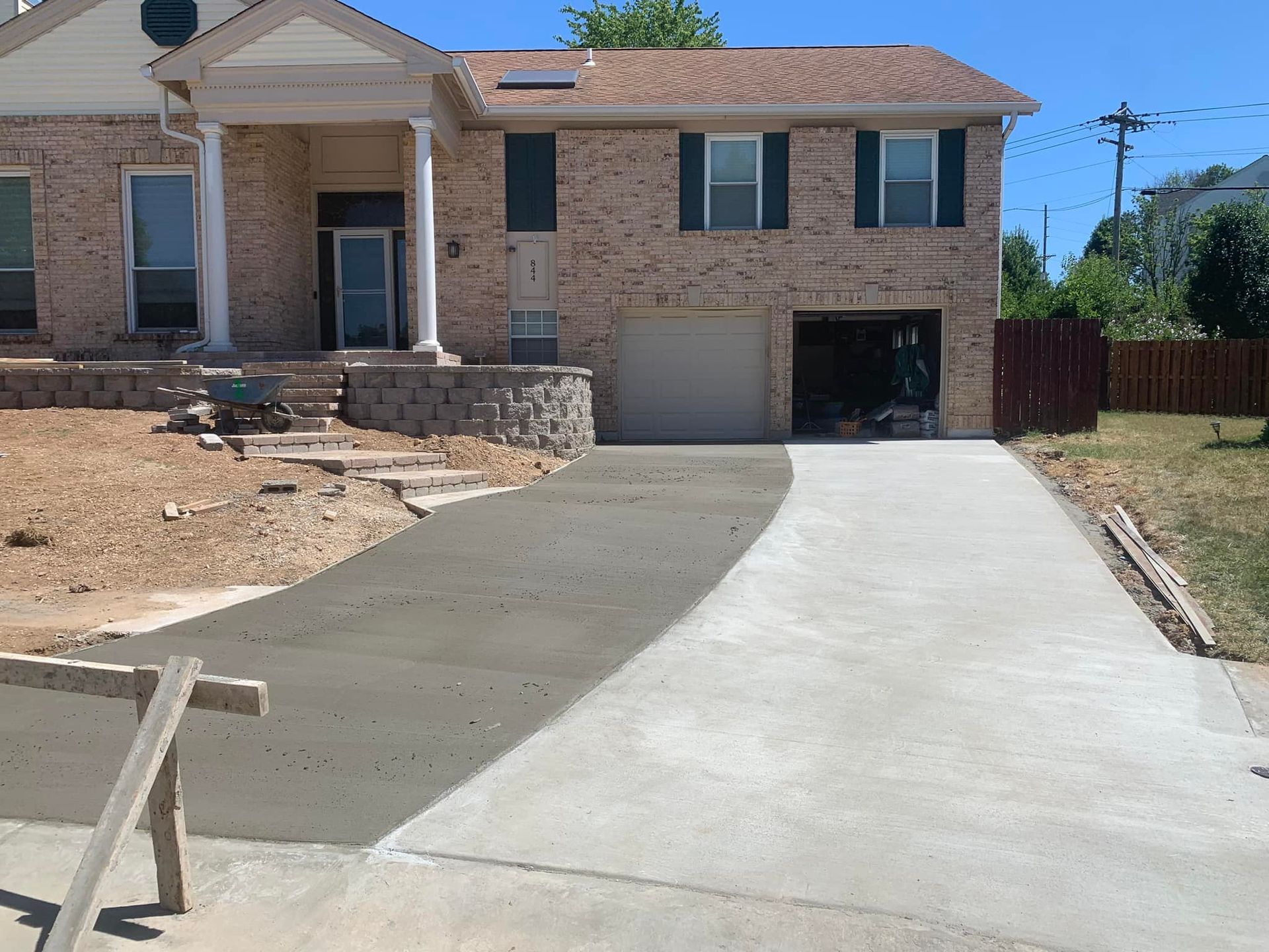 Newly poured concrete driveway leading to a brick house with a garage.