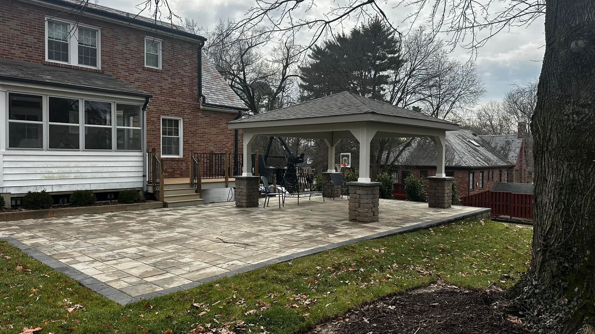 Backyard patio with gazebo, brick house, and green grass.