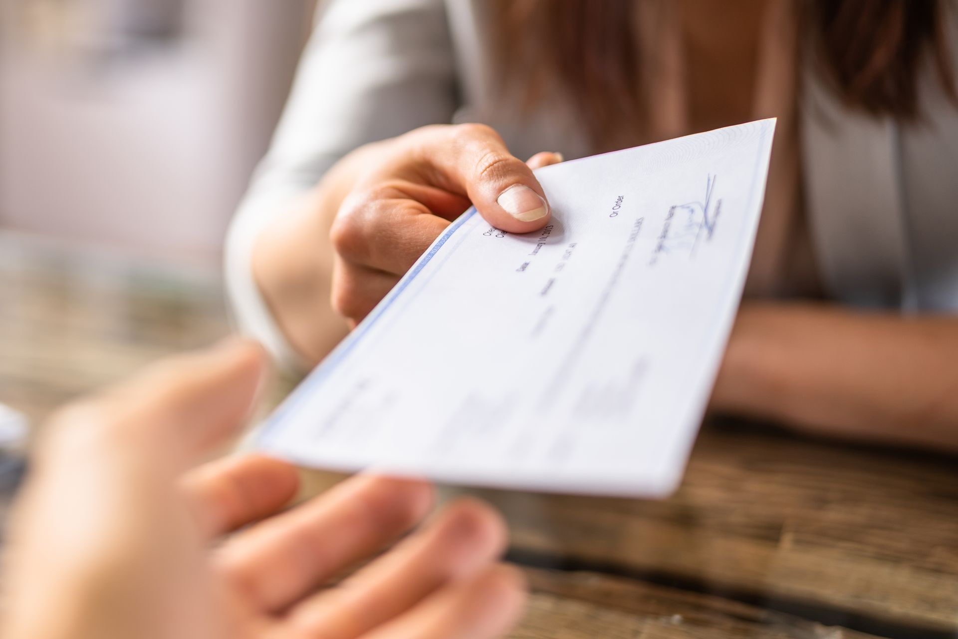 A woman is handing a check to another woman.