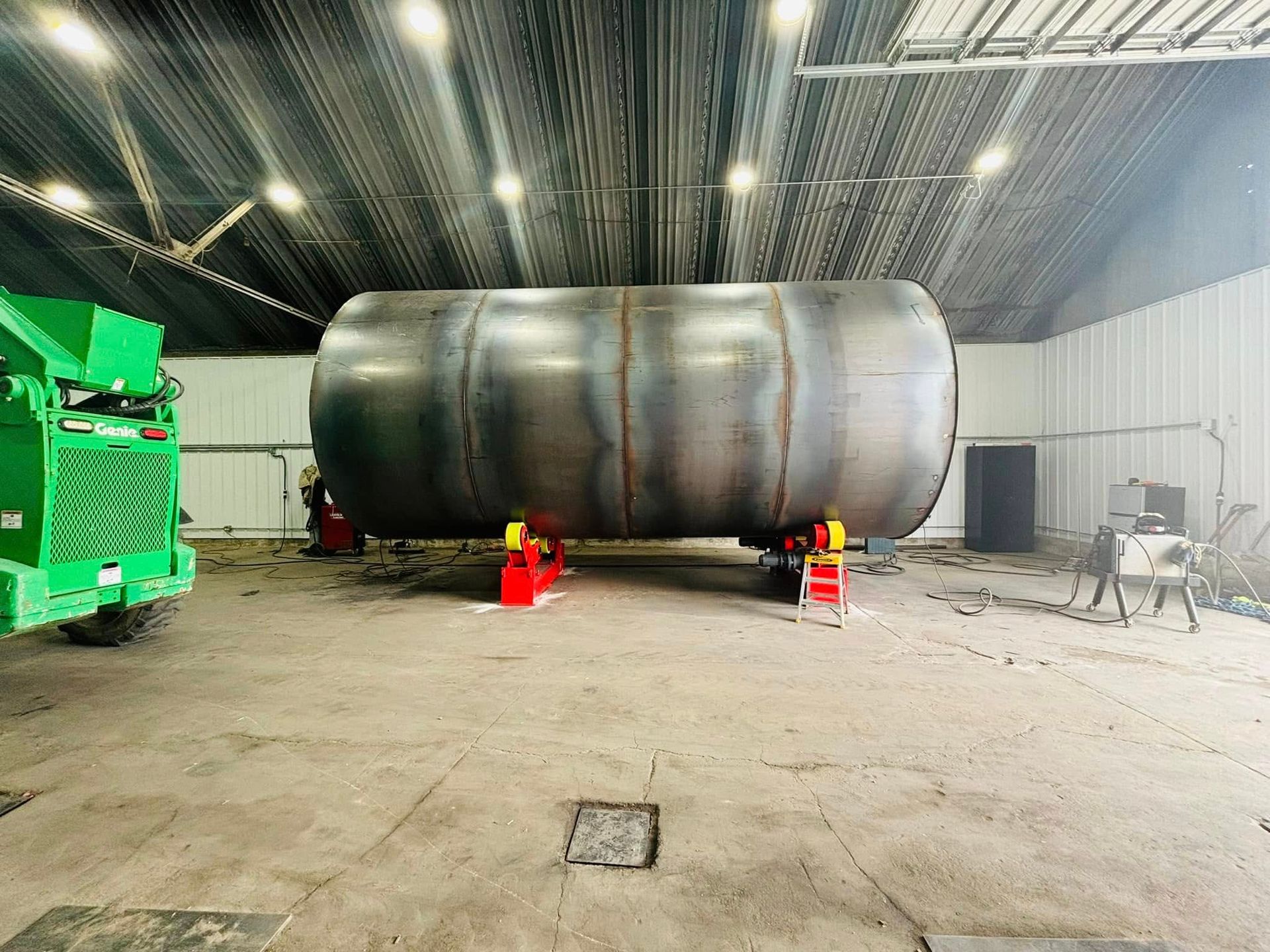 A large metal tank is sitting in a warehouse next to a green truck.