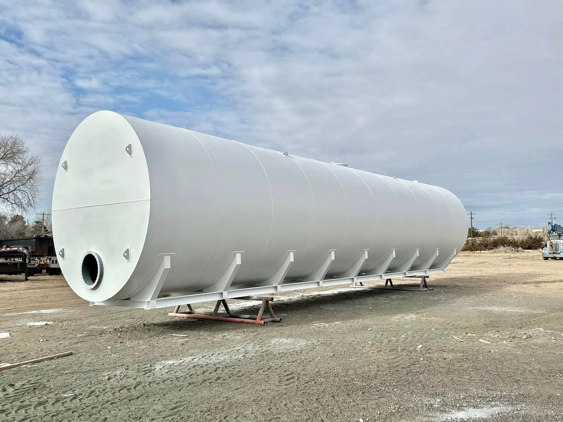 A large white tank is sitting on top of a gravel field.