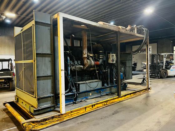 A large machine is sitting in a warehouse with a forklift in the background.