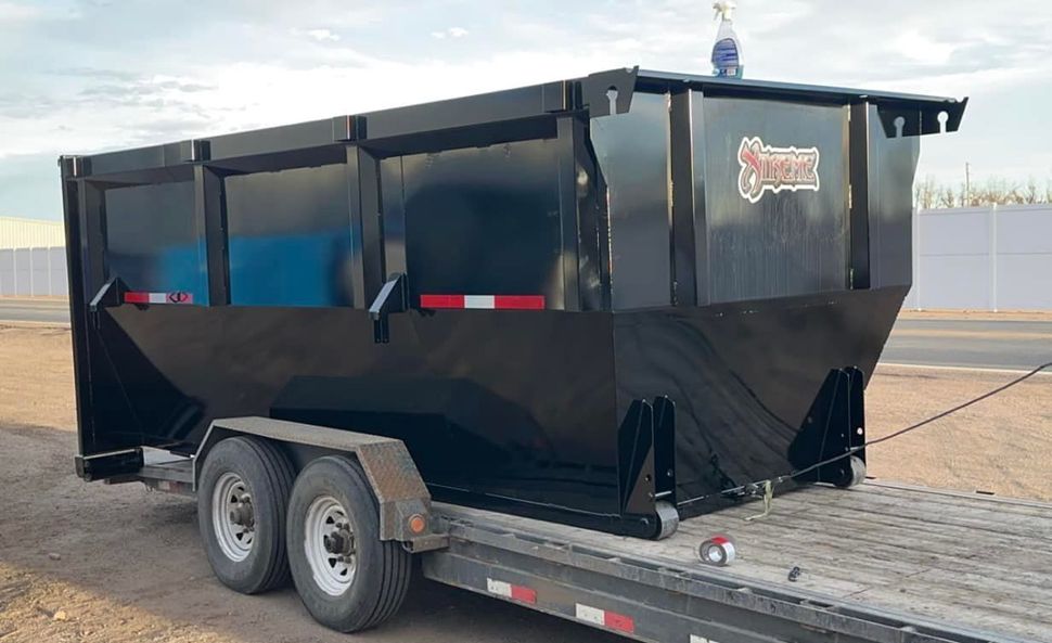 A dumpster is sitting on top of a trailer.