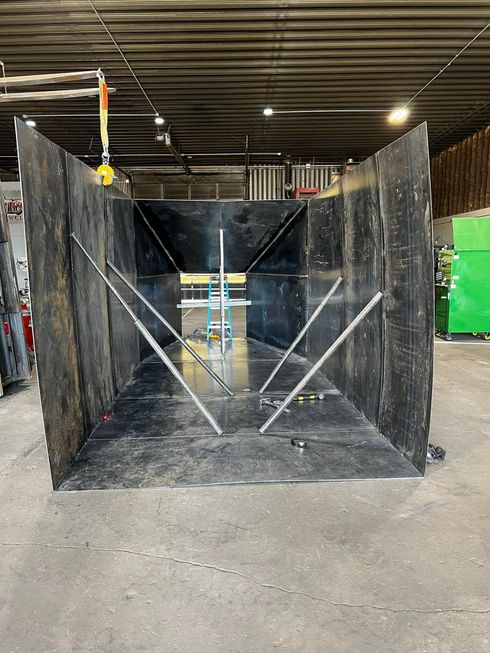 A large metal box is sitting on the ground in a warehouse.