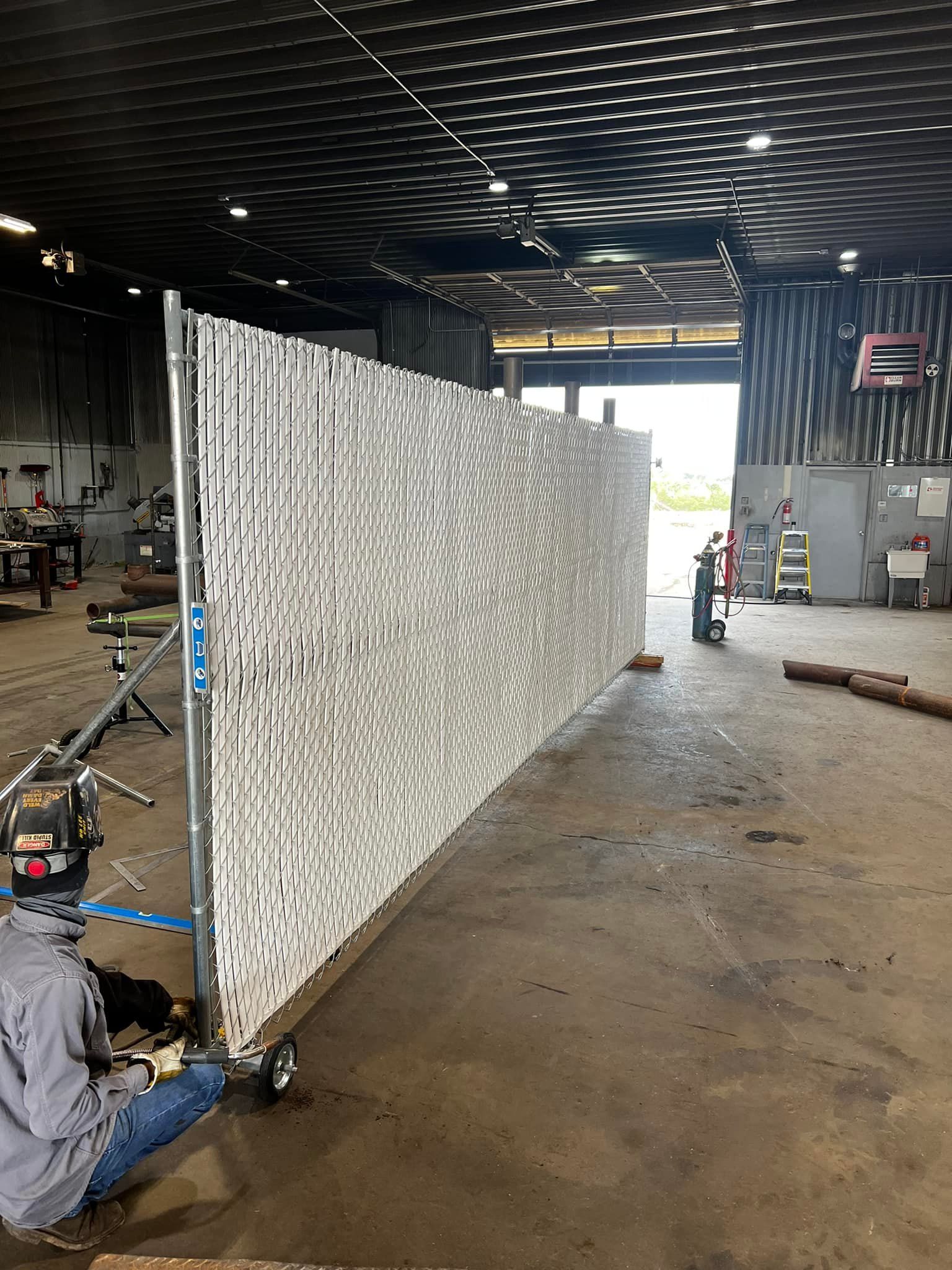 A man is working on a chain link fence in a factory.