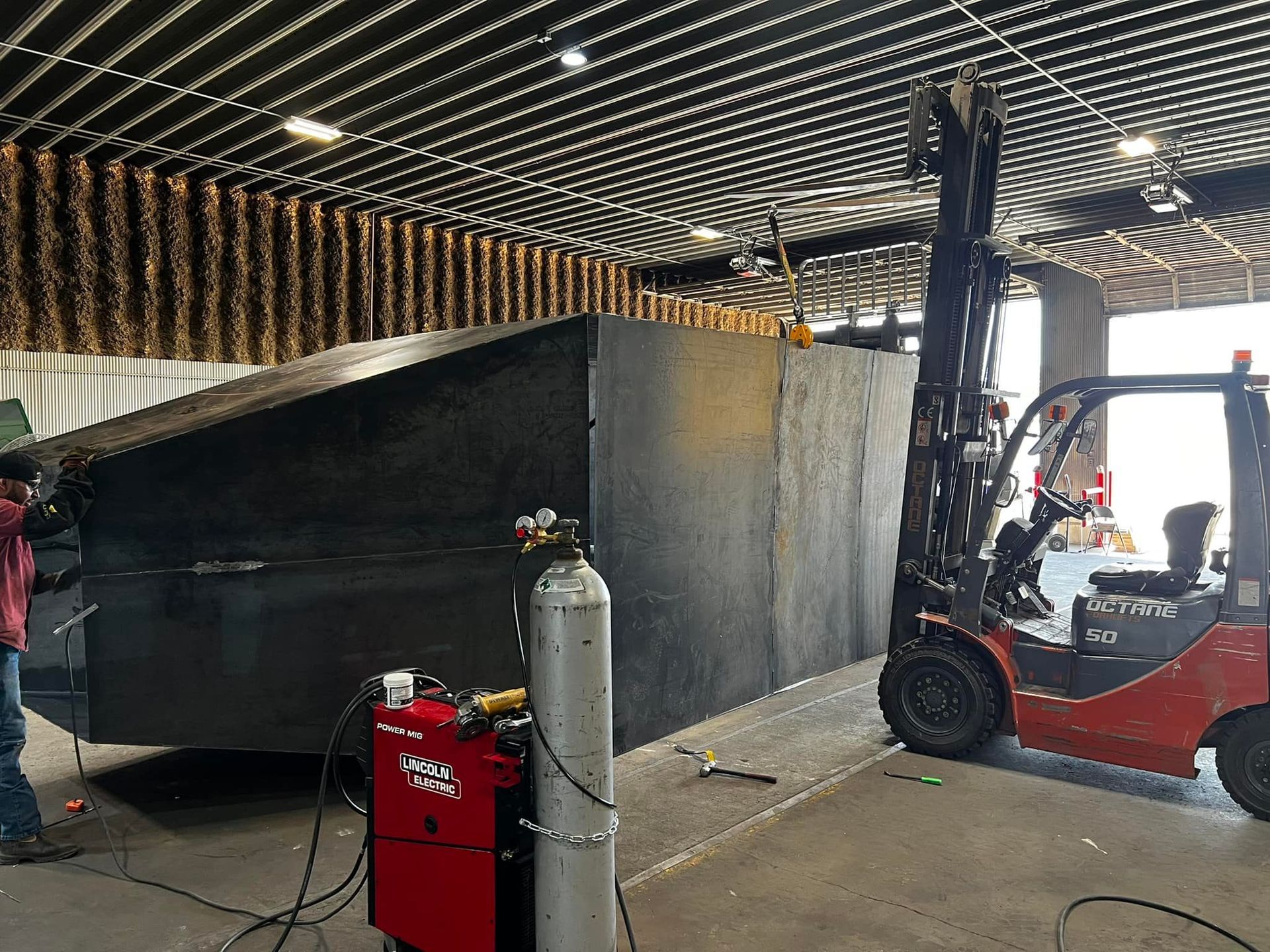 A forklift is carrying a large piece of metal in a garage.