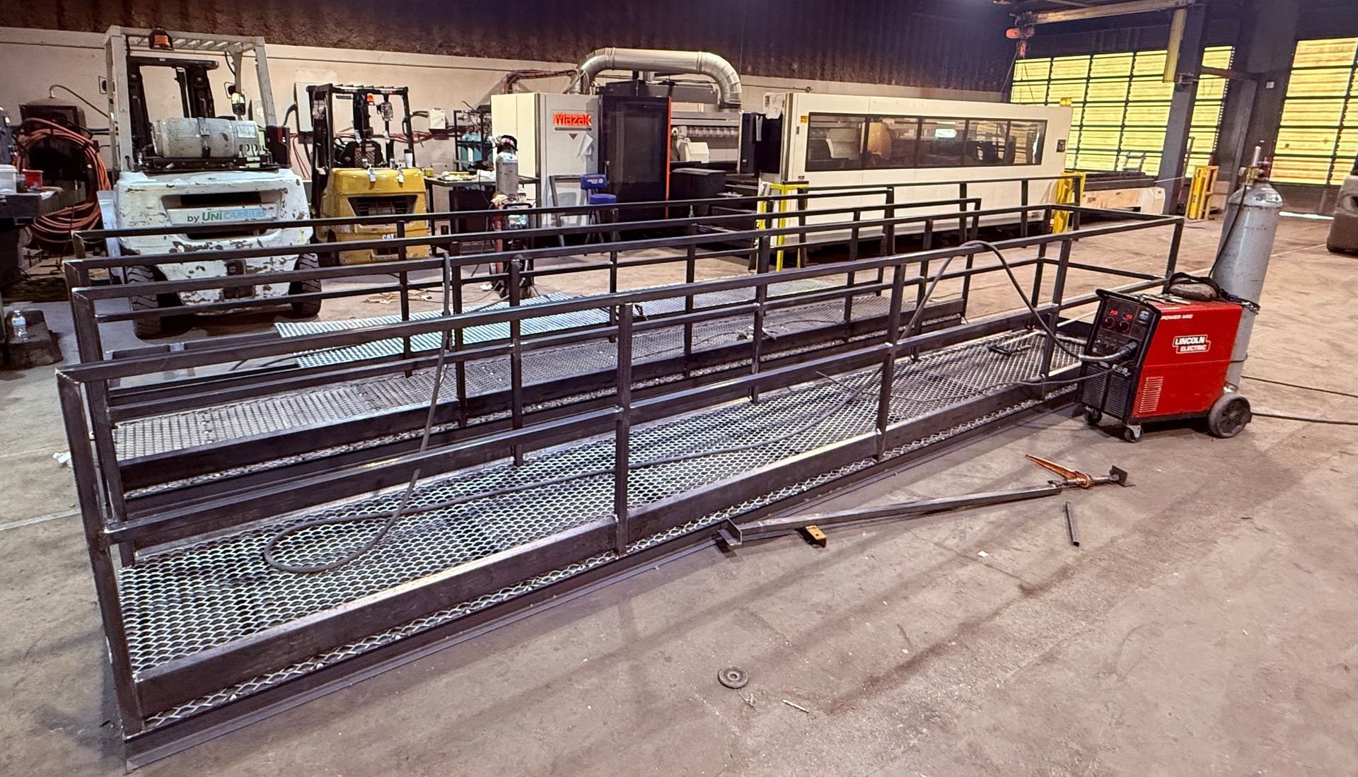 A large metal tank is sitting in a warehouse next to a green truck.