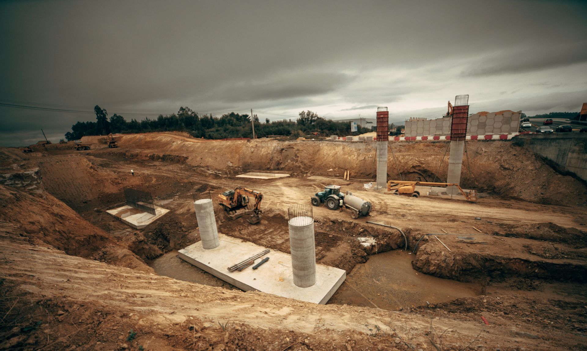 A construction site with a lot of dirt and concrete pillars.