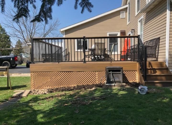 A wooden deck with black railing and lattice siding; outdoor seating.