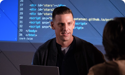Man presenting code to someone, with code projected on a screen.