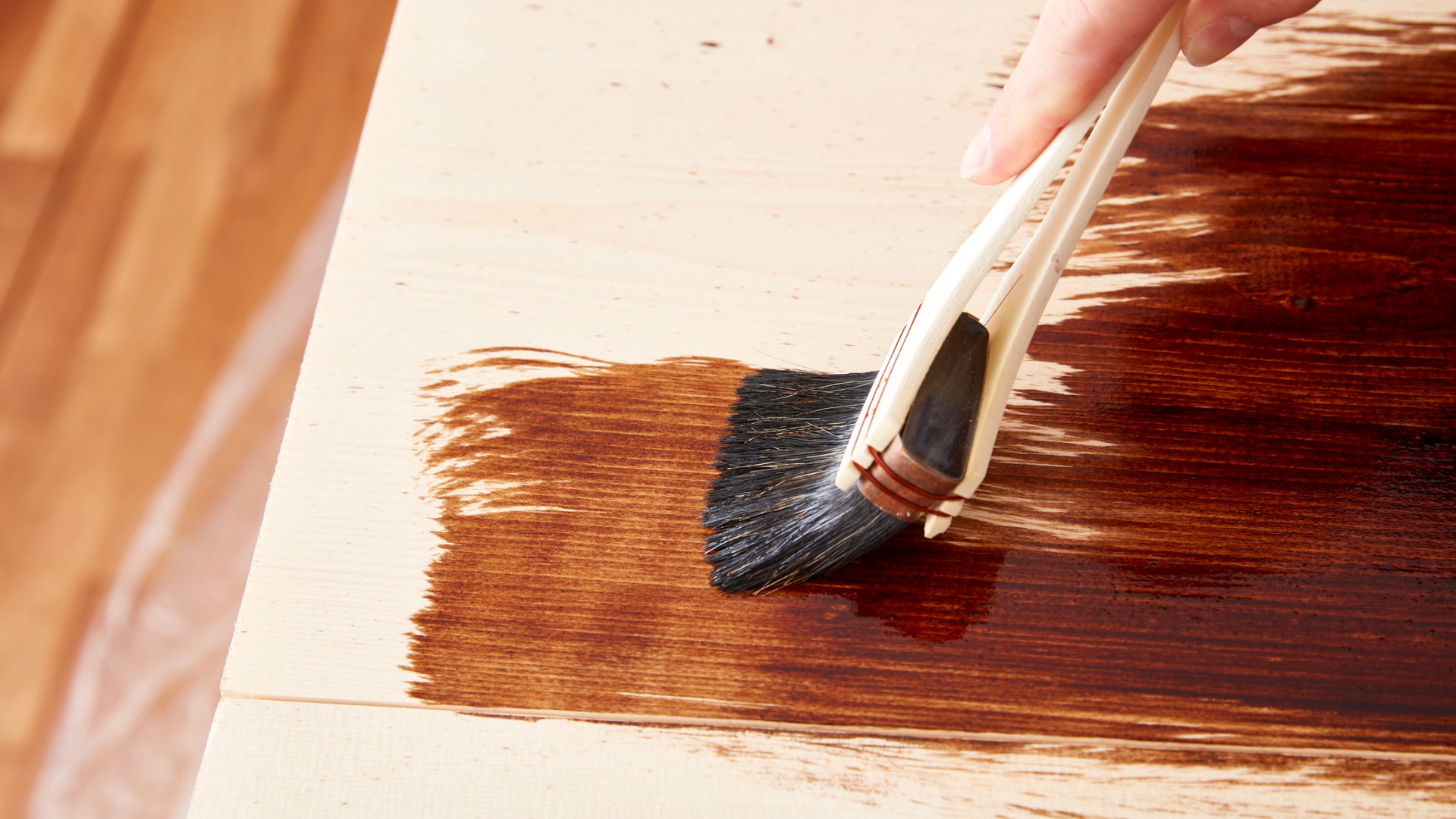 A person is painting a piece of wood with a brush.