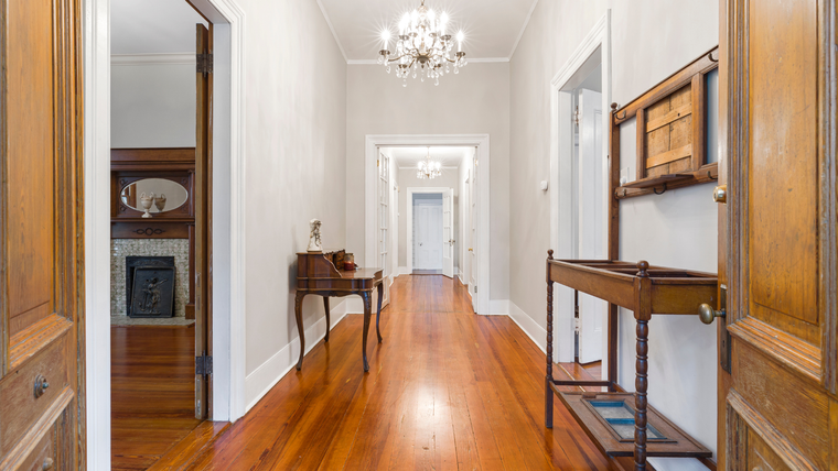 A long hallway with wooden floors and a chandelier.