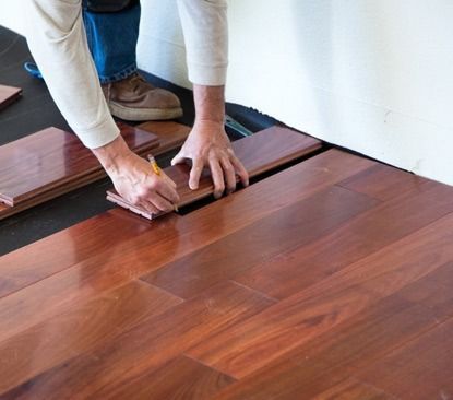 A person is installing a wooden floor in a room.