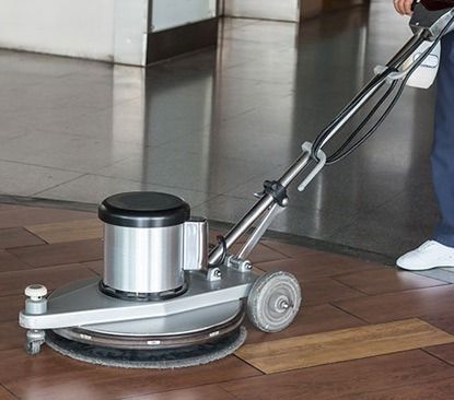 A person is using a machine to clean a wooden floor.