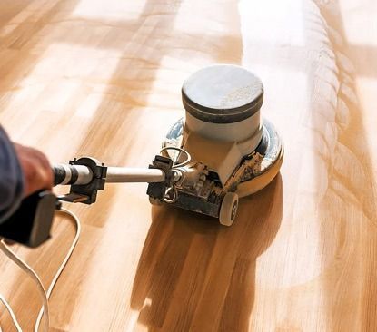 A person is using a machine to polish a wooden floor.