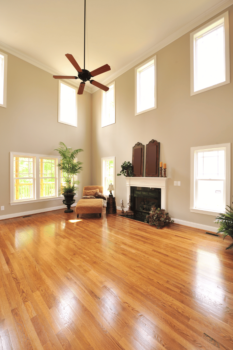 A living room with hardwood floors , a fireplace and a ceiling fan.