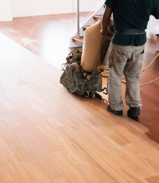 A man is sanding a wooden floor with a machine