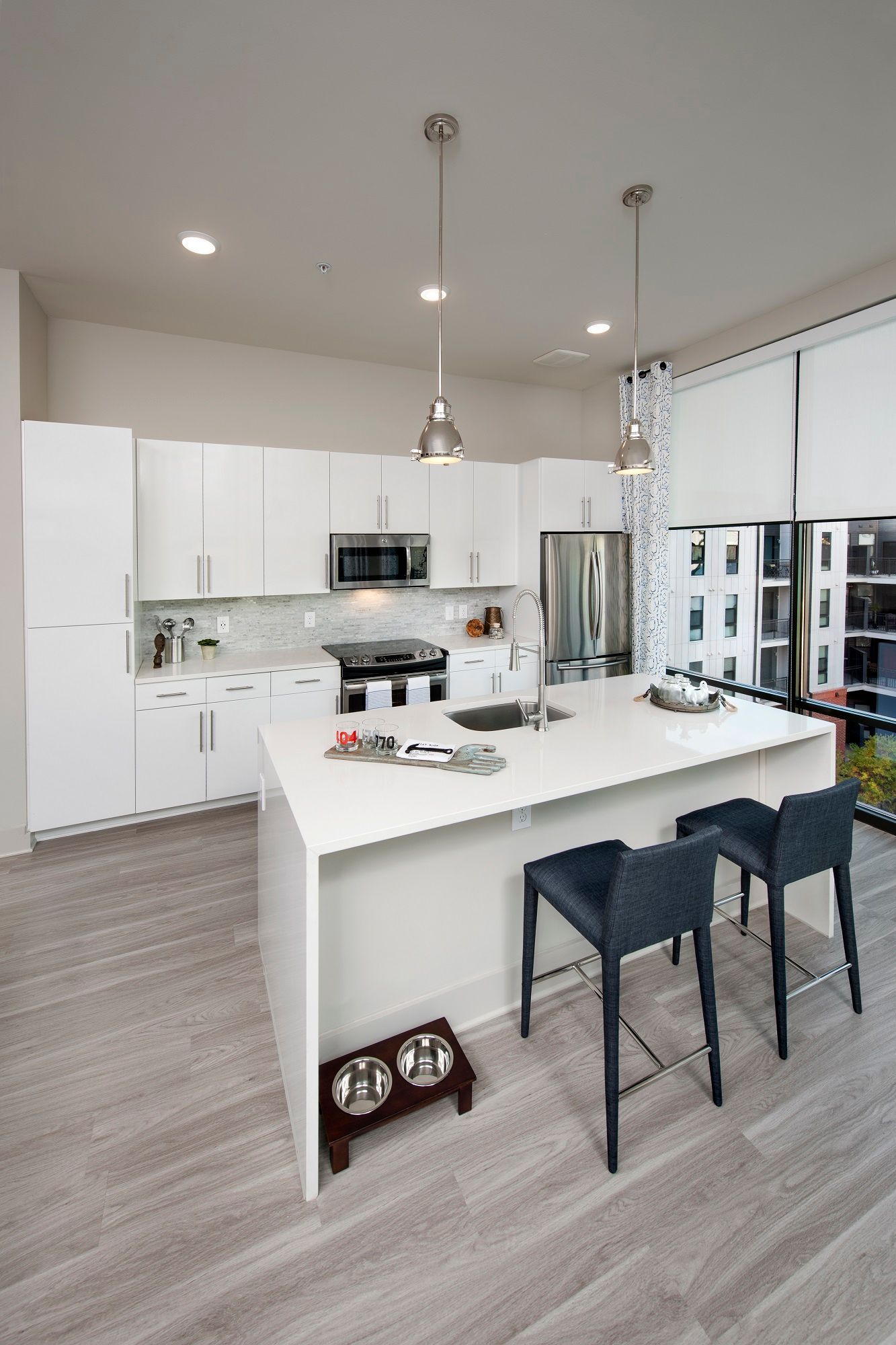 A kitchen with white cabinets, stainless steel appliances, and a large island.