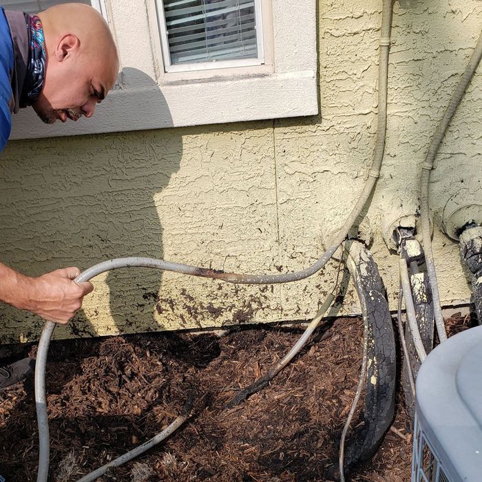 A man is holding a hose in front of a house.