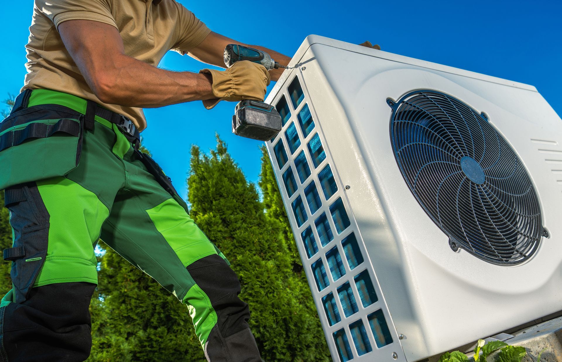 A man is working on an air conditioner with a drill.