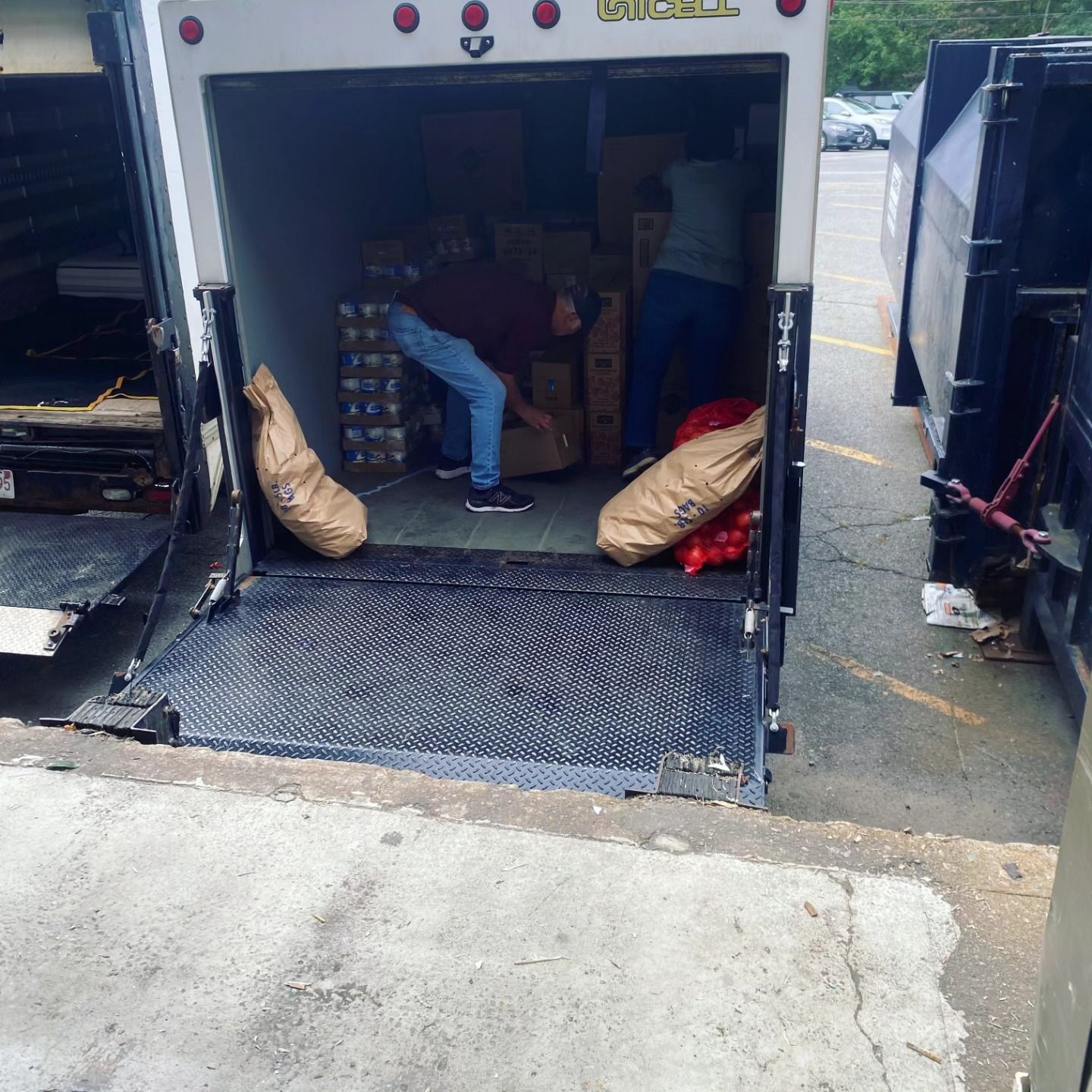 A man sits in the back of a truck with a license plate that says ' lc ' on it