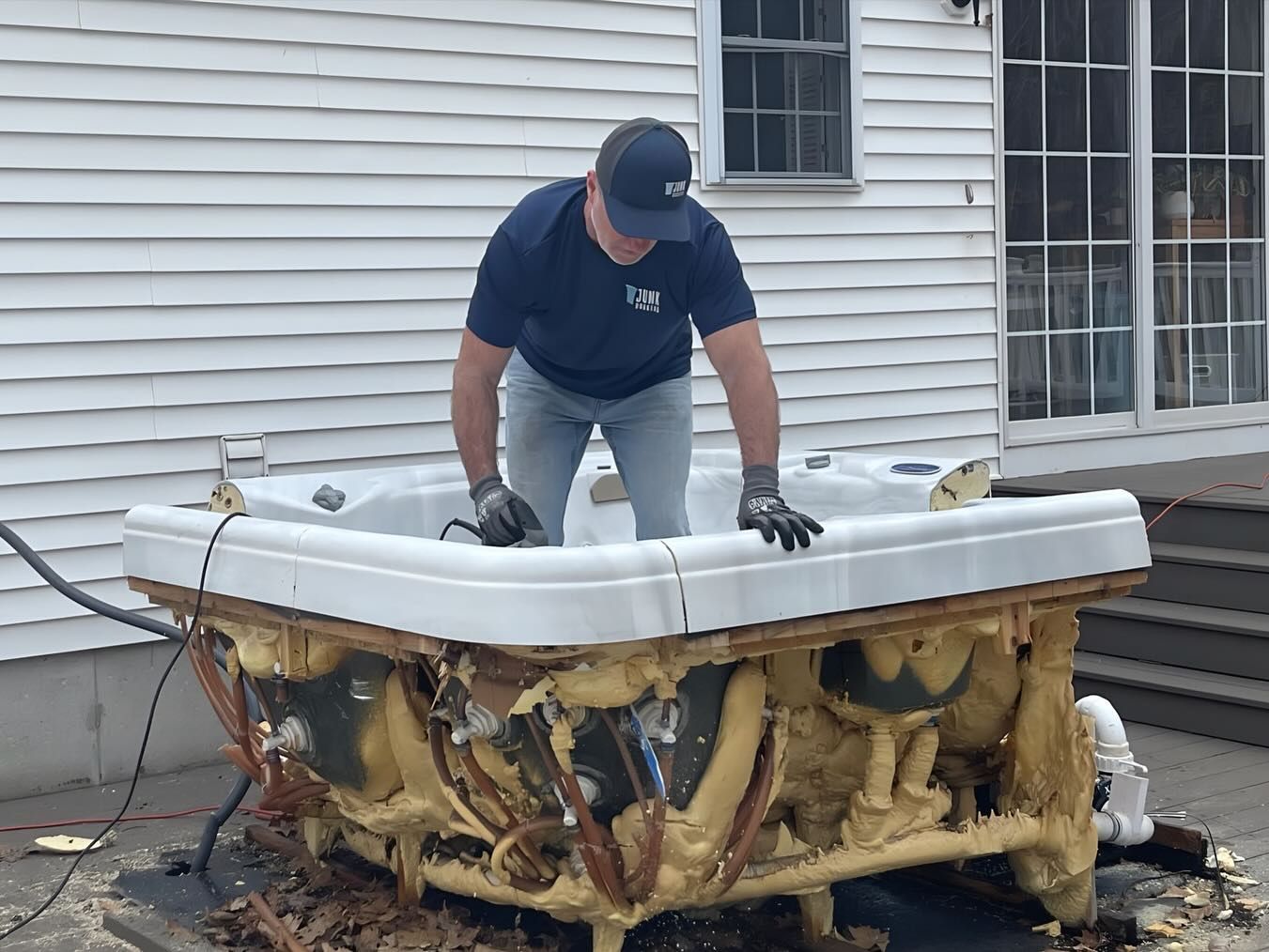 A man is working on a hot tub outside of a house.