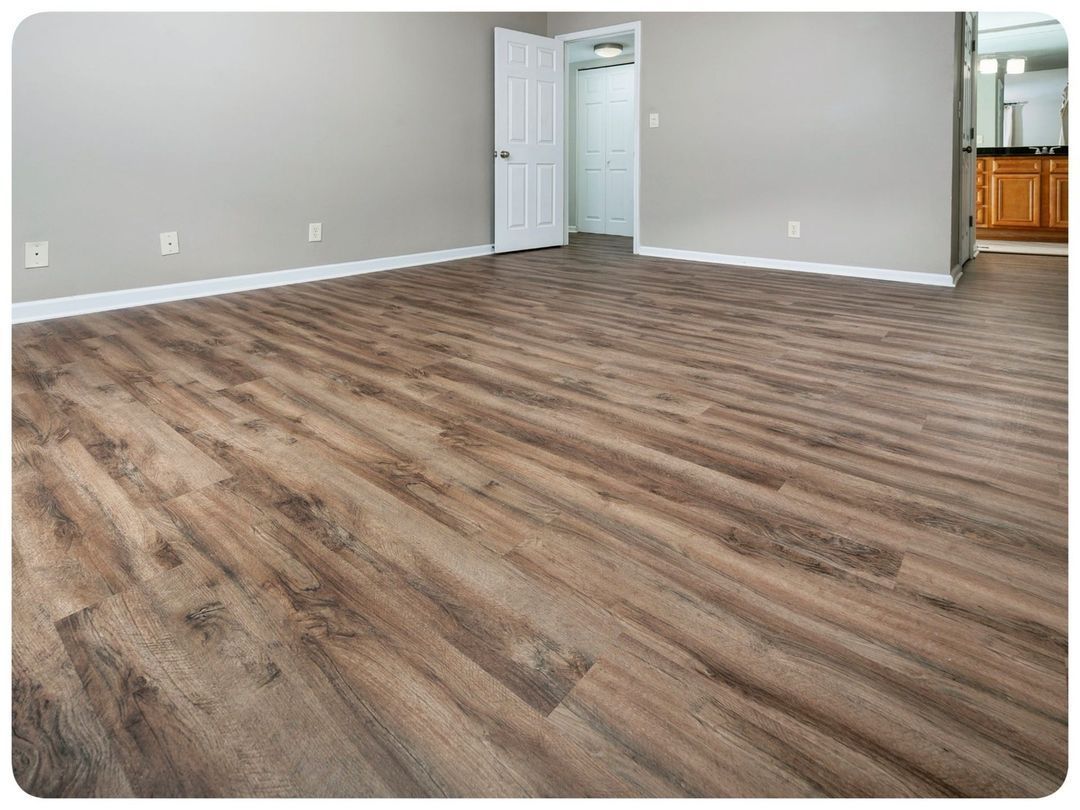 A living room with a wooden floor and a door leading to a kitchen.