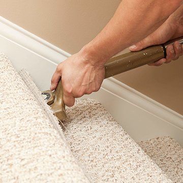 A person is using a tool to remove carpet from a staircase.