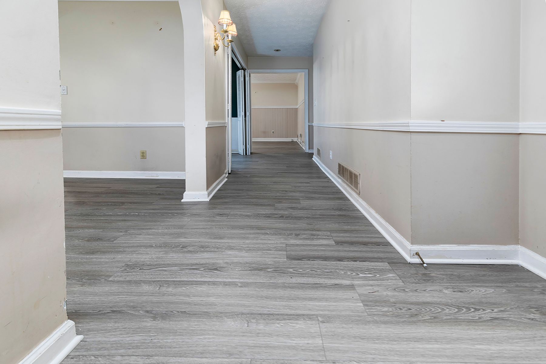 An empty hallway with hardwood floors and white trim in a house.