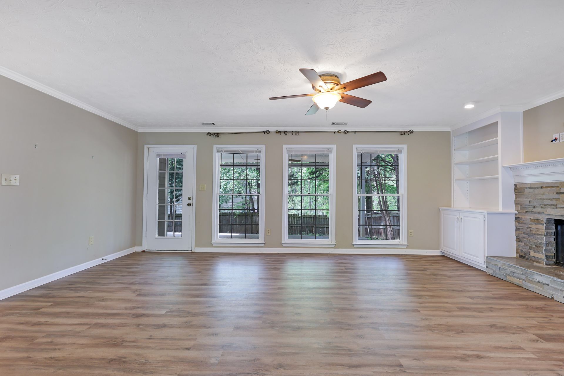 An empty living room with hardwood floors and a ceiling fan.