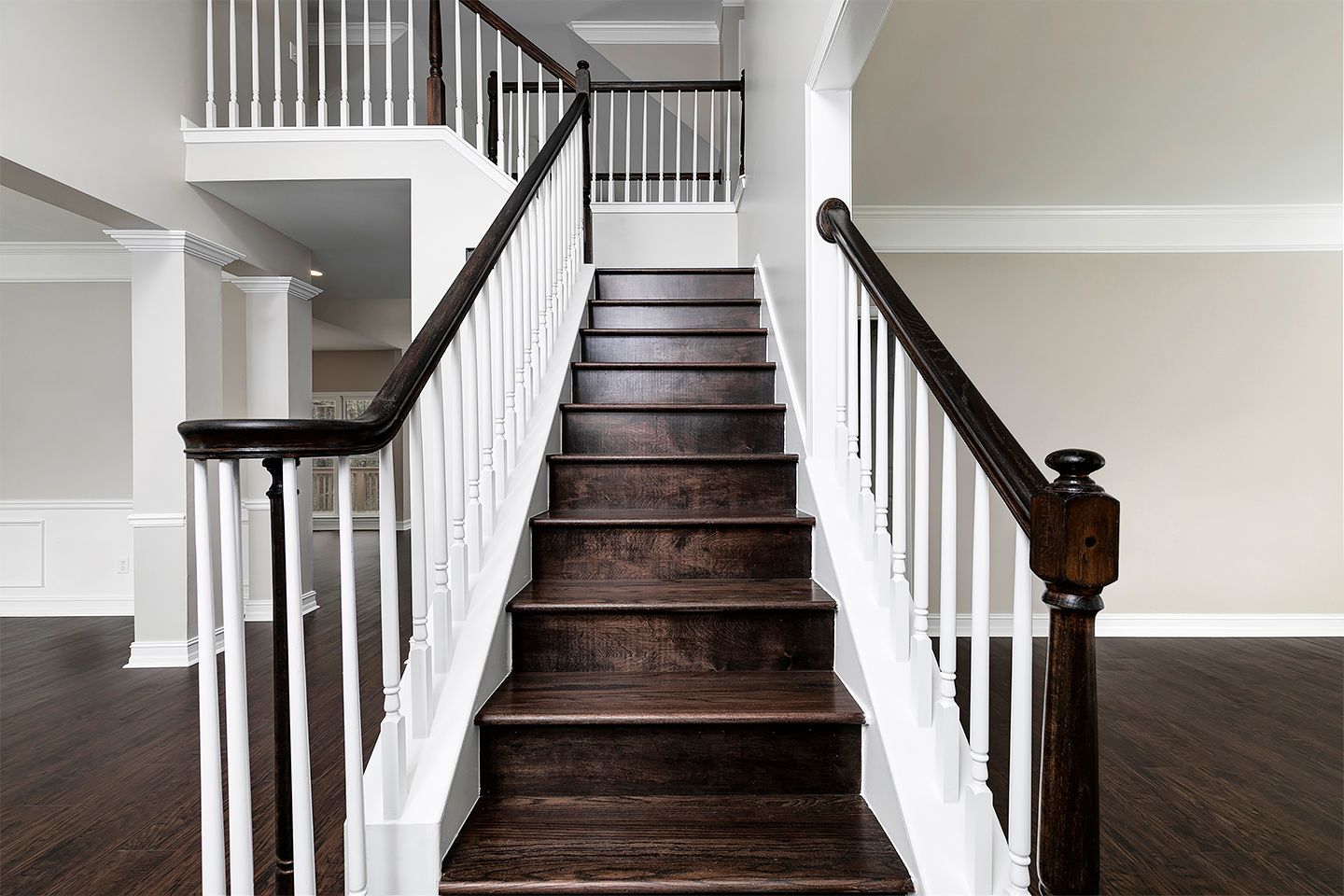 A wooden staircase with a white railing in an empty house.