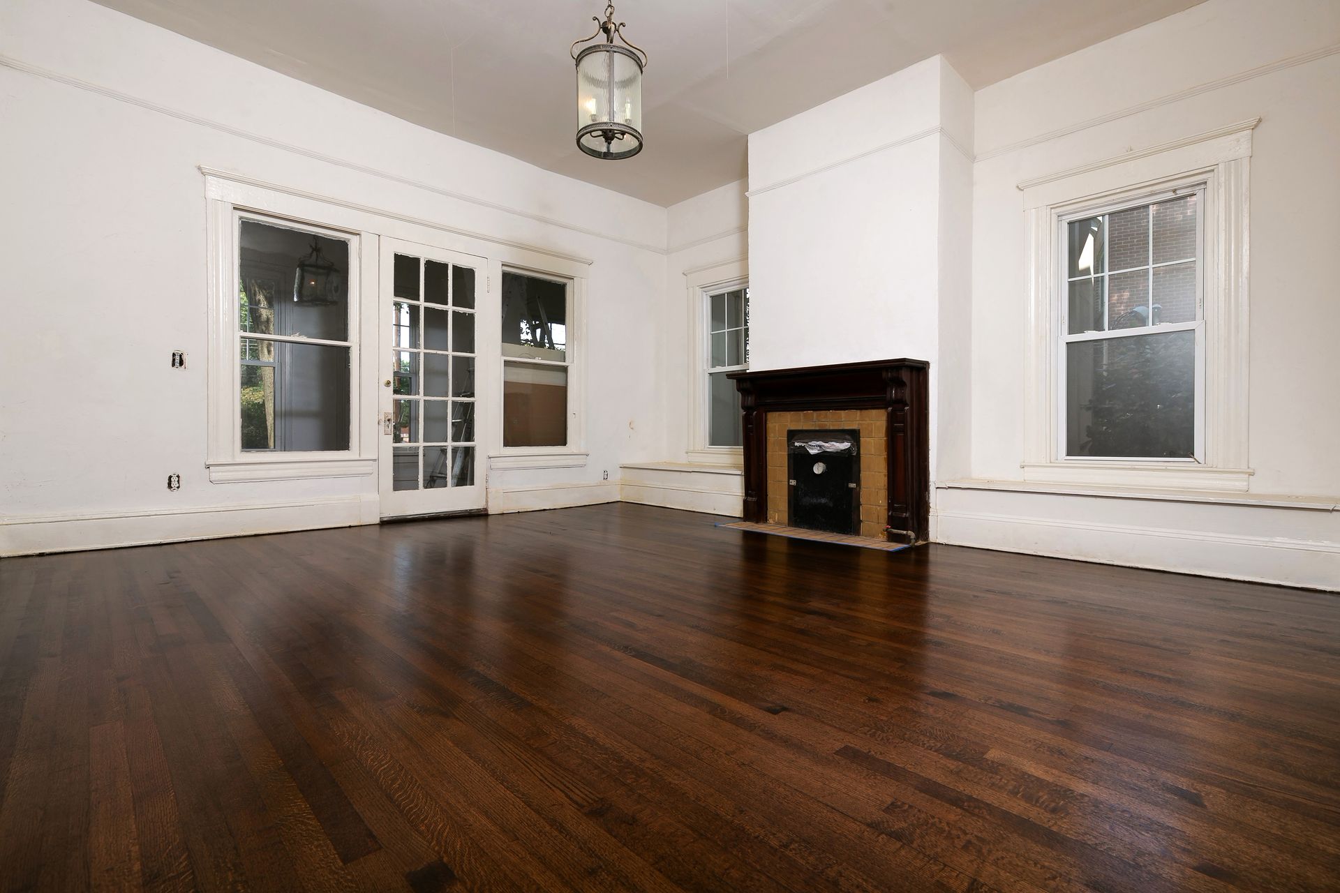 An empty living room with hardwood floors and a fireplace