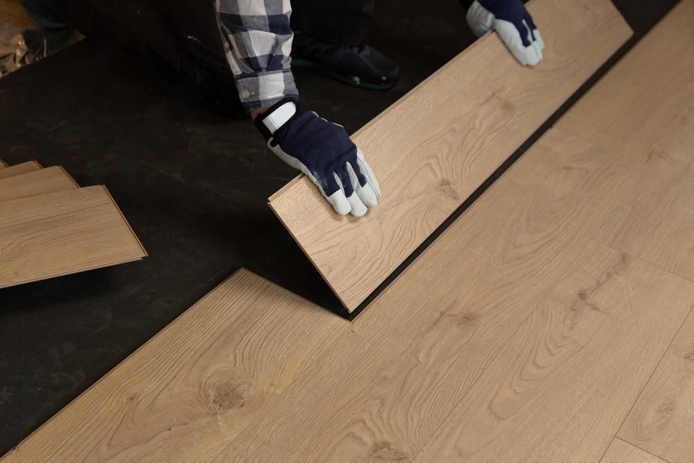 a person is installing a wooden floor in a room .