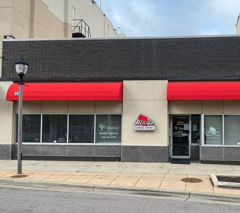 Exterior of a business with a red awning, windows, and a black brick upper facade.