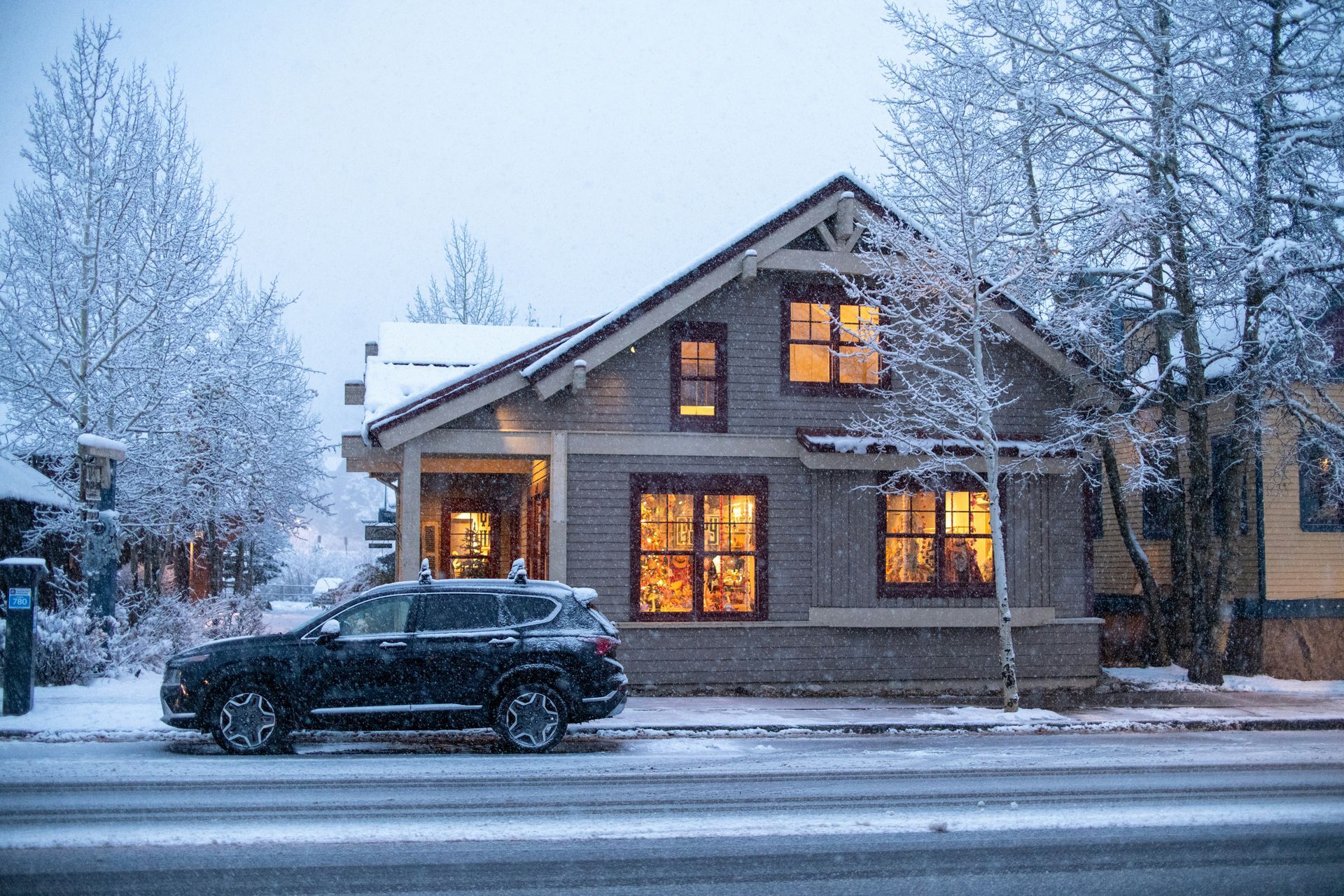 A car is parked in front of a house in the snow.