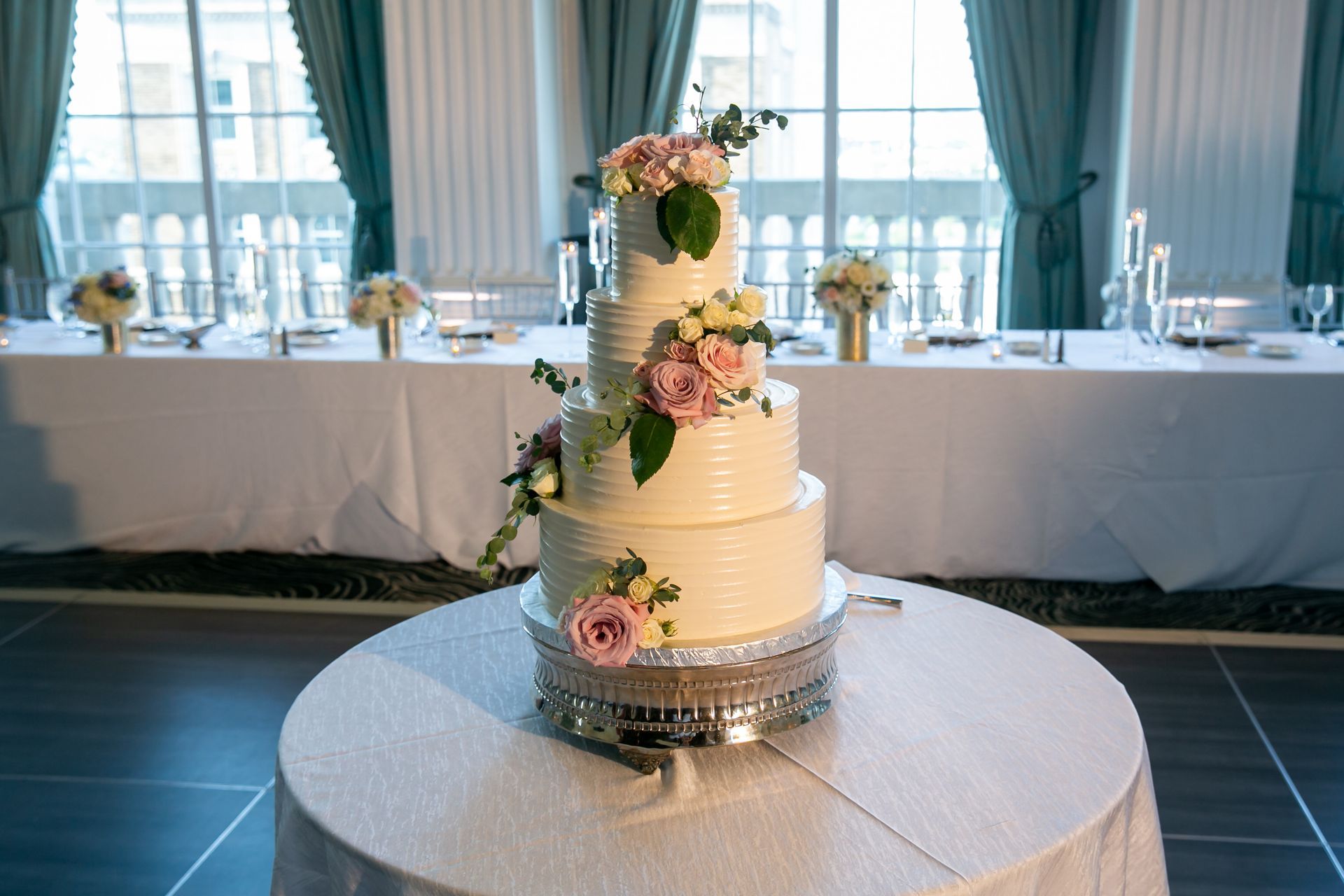A wedding cake is sitting on a table in front of a long table.