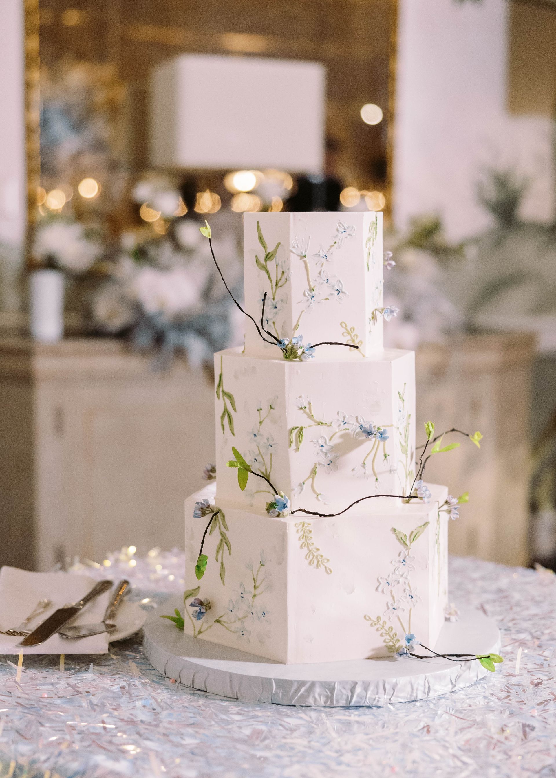 A white wedding cake with flowers on it is sitting on a table.
