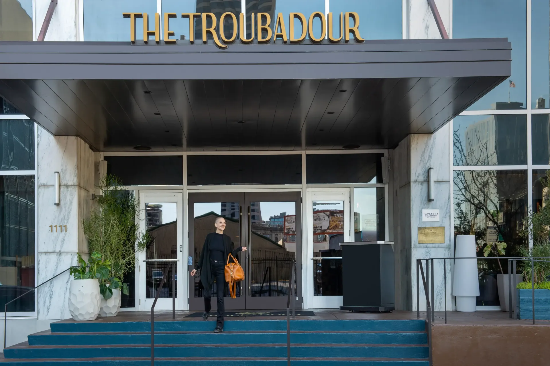 A man is standing in front of the troubadour hotel.