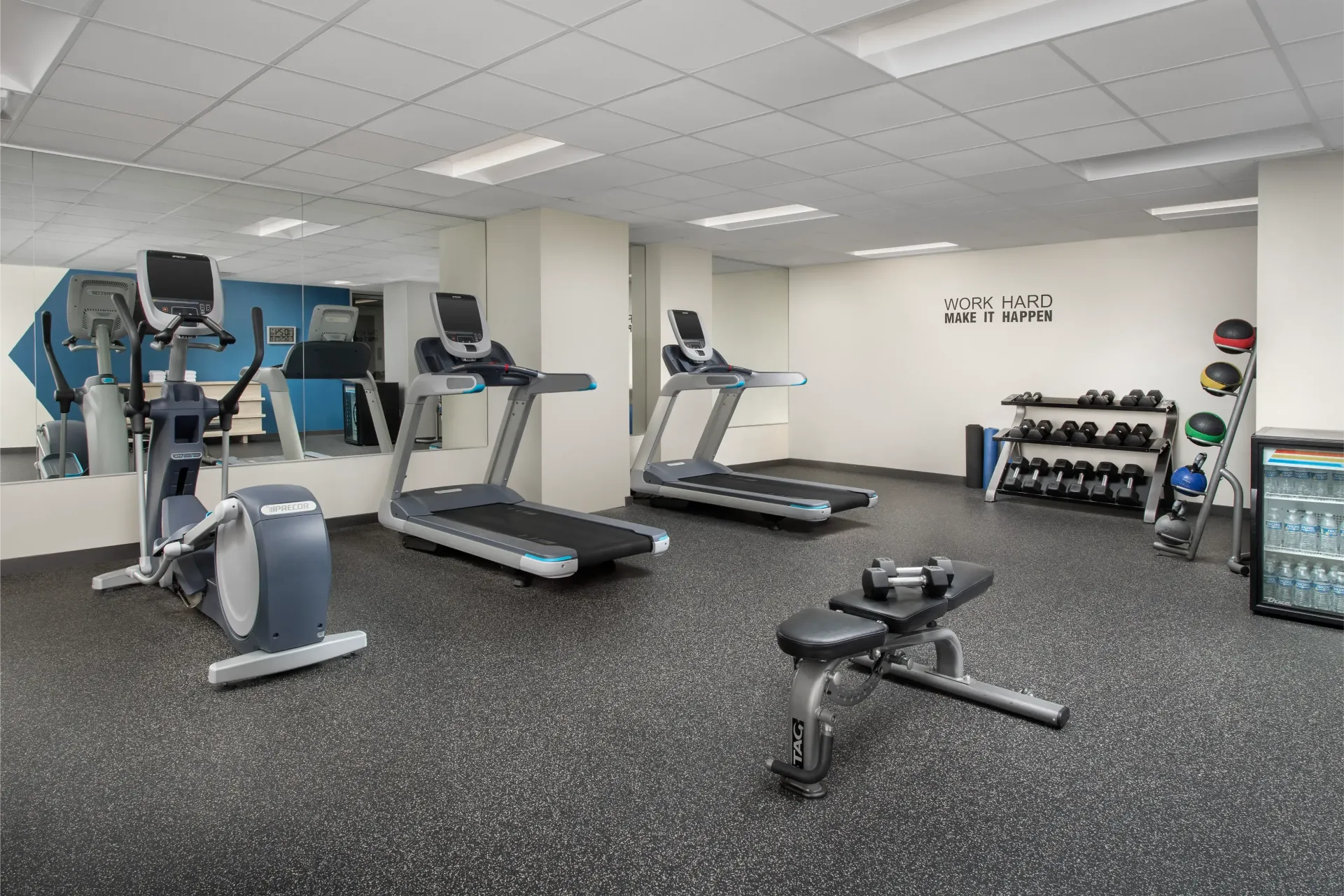 A gym with treadmills , ellipticals , and dumbbells.