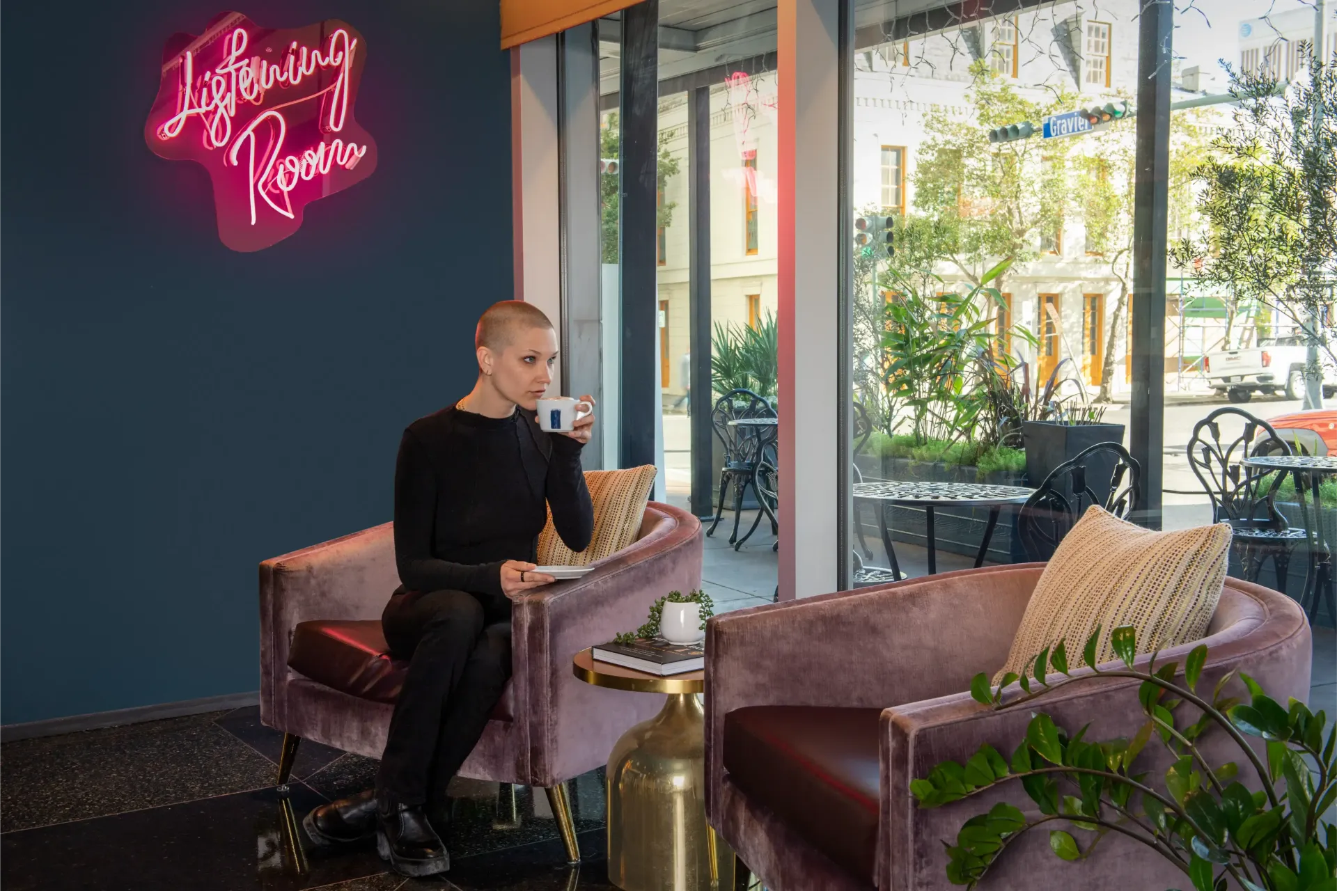 A woman is sitting in a chair drinking a cup of coffee.