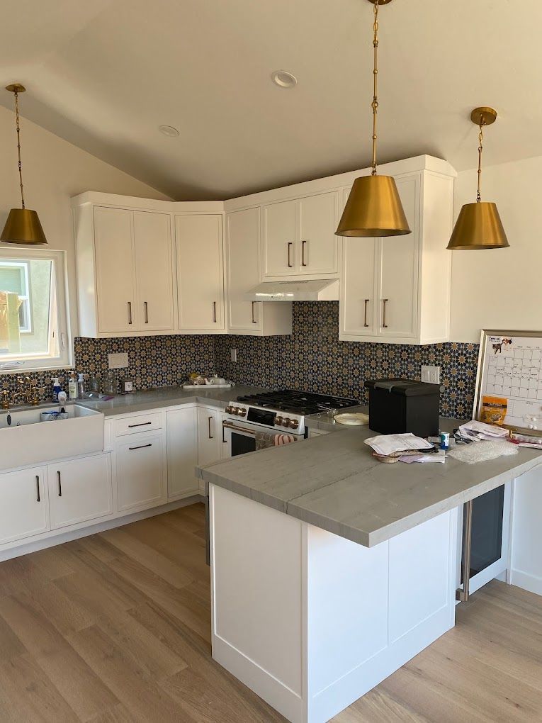 A kitchen with white cabinets , a stove , a sink , and a large island.