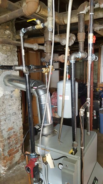 Boiler with pipes and metal flue in a basement setting.