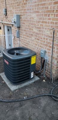 An air conditioning unit next to a brick building.
