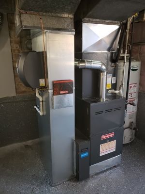 Furnace and hot water heater in a basement. Metal air ducts and pipes. Concrete floor.
