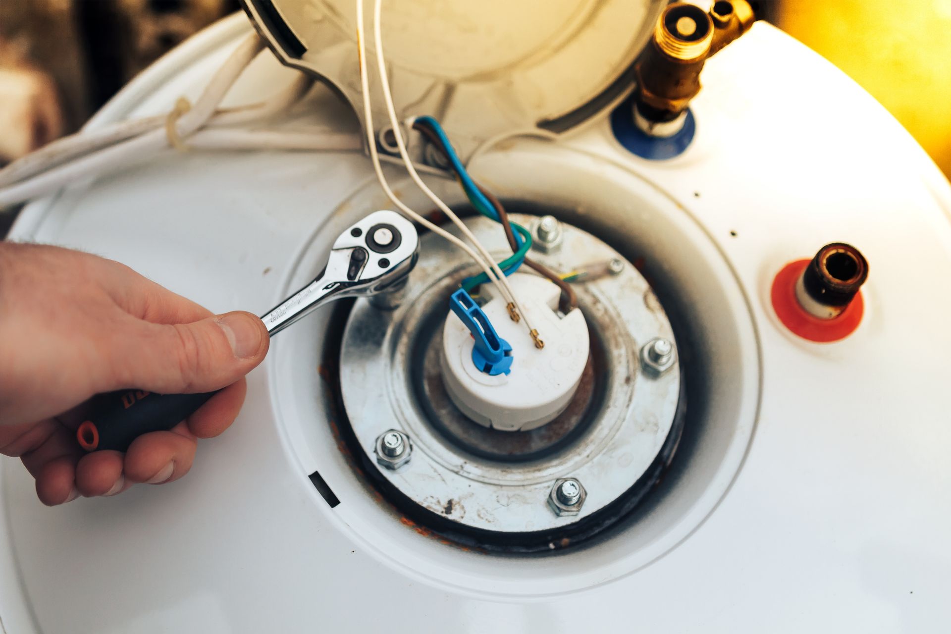 Hand using wrench to work on a water heater, close up.
