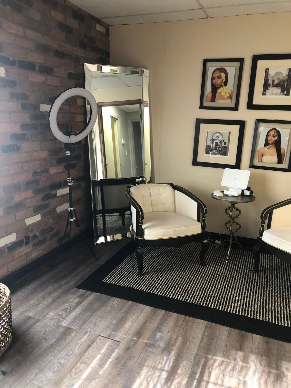 A room with a brick wall, mirror, ring light, chairs, and framed photos; likely a studio.