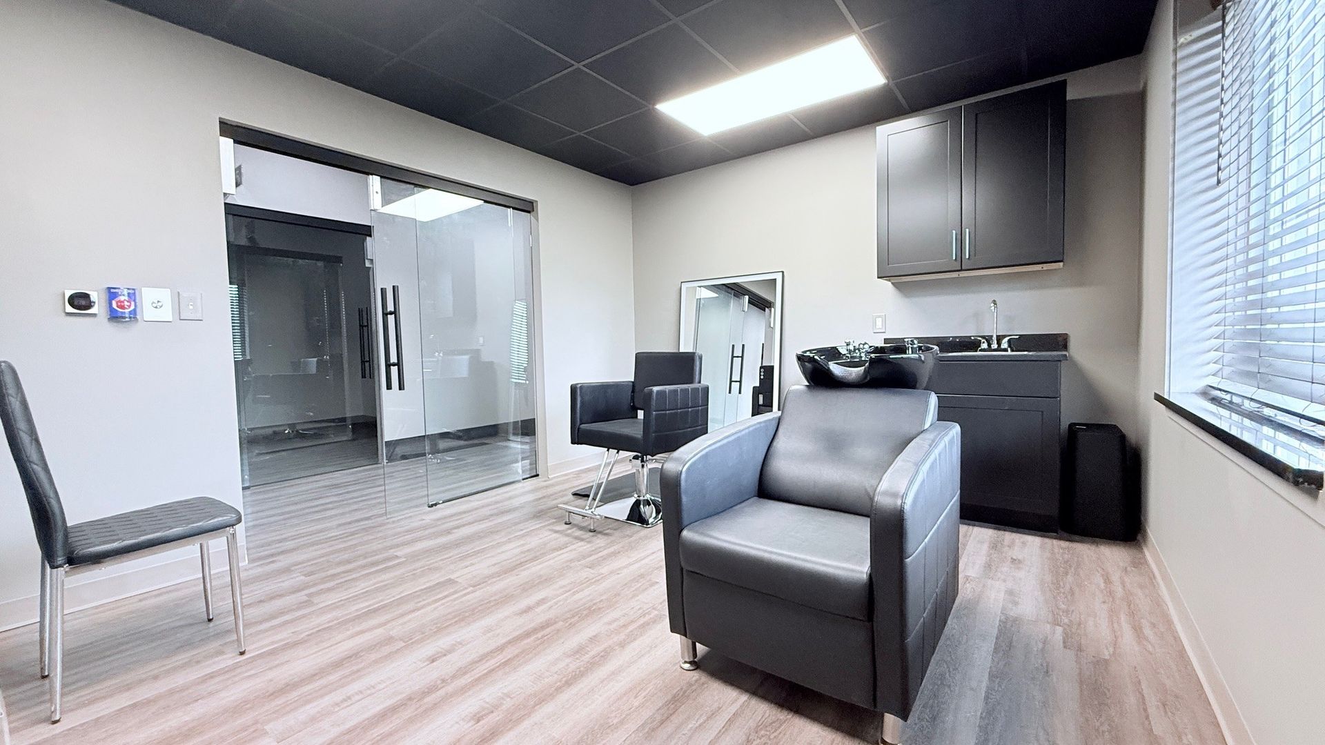 Hair salon interior with a shampoo chair, cabinets, and a chair.