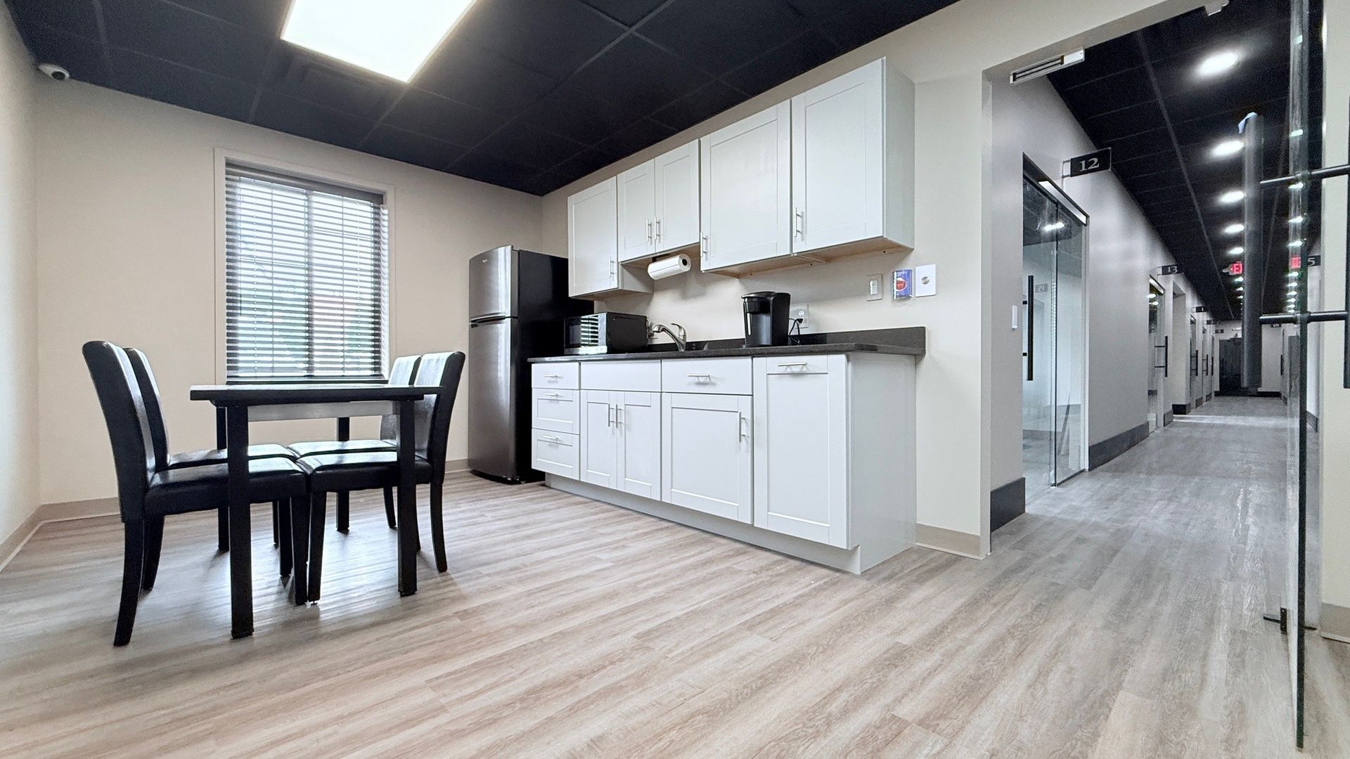 Kitchen area with cabinets, appliances, table, chairs, and a hallway leading to several doors.