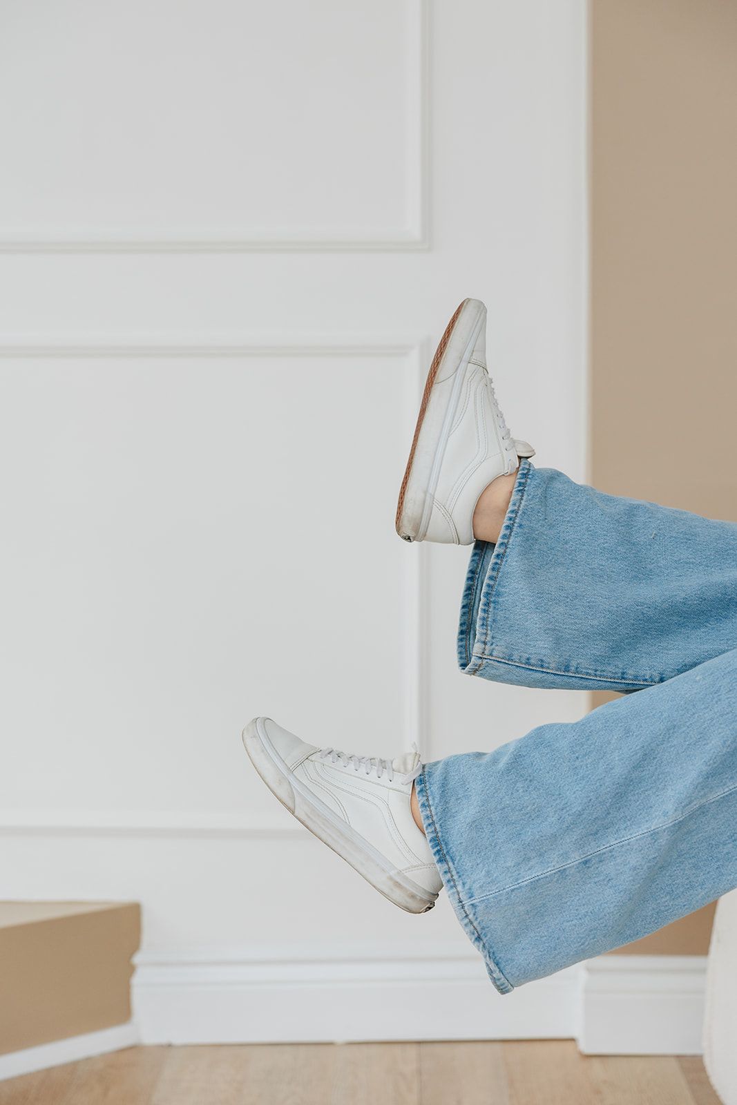 A person wearing jeans and white sneakers is flying through the air.